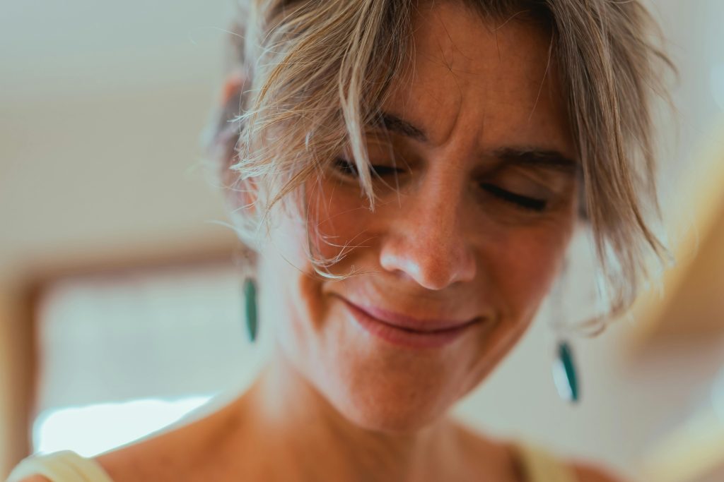 Close-up of a smiling middle-aged woman with closed eyes, embracing positive aging indoors.