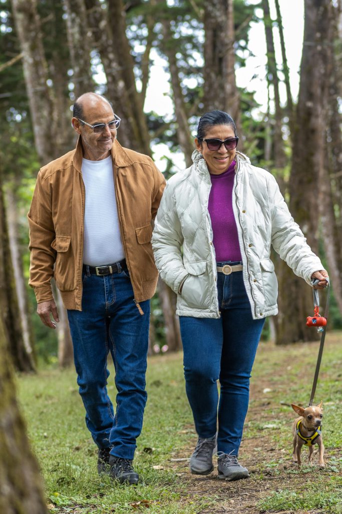 Senior couple enjoying leisure walk with Chihuahua in a forest park.